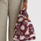 model holding maroon baby baggu with various dogs with ribbons tied around their necks