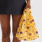 model carrying yellow baby baggu with pompompurin and pink flowers