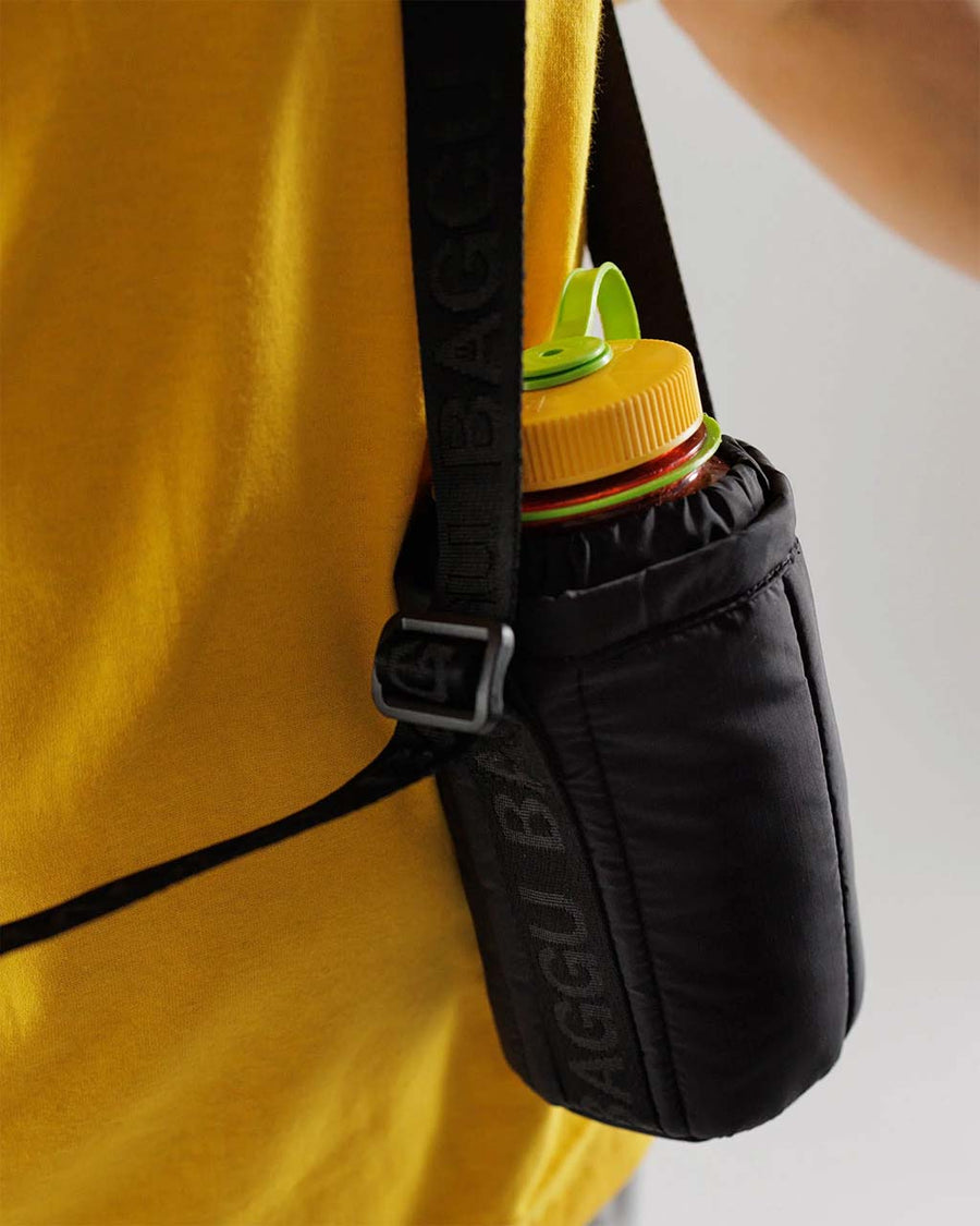 up close of model wearing black puffy water bottle sling
