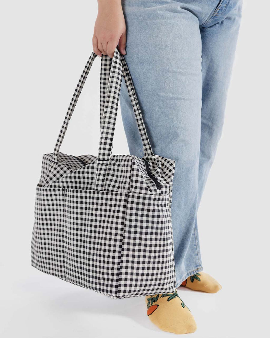 model holding white and black gingham baggu cloud carry-on bag