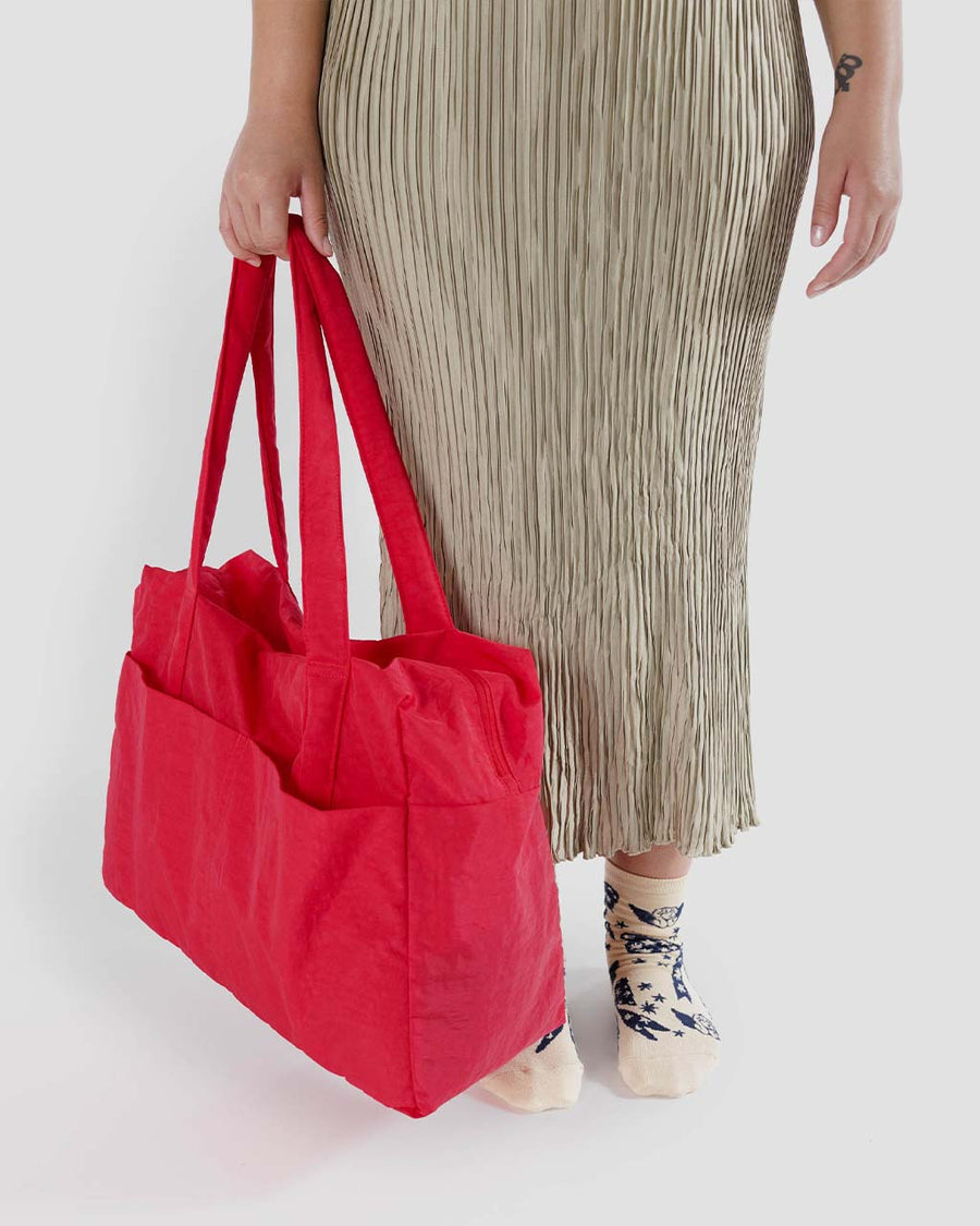model holding candy apple red baggu cloud carry-on bag
