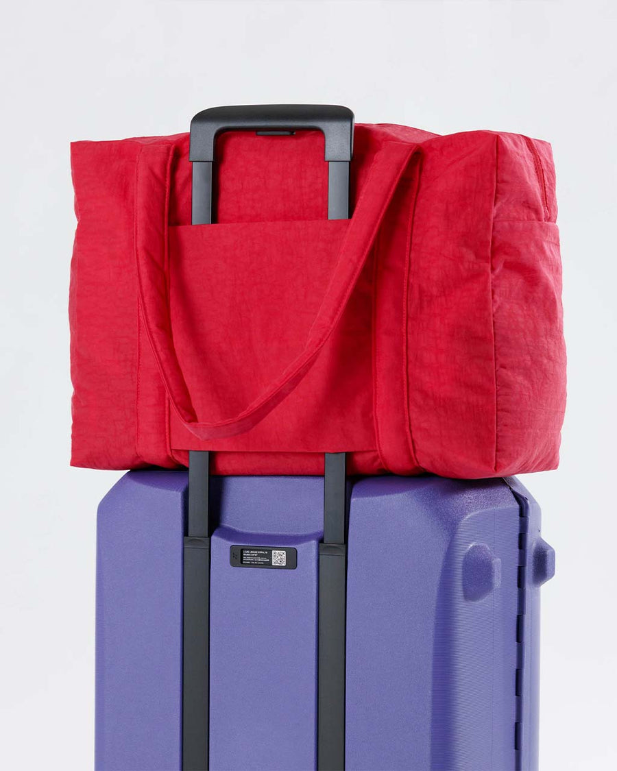 candy apple red baggu cloud carry-on bag on suitcase