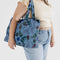 model carrying blue digital denim nylon cloud carry on bag with colorful floral and bird print