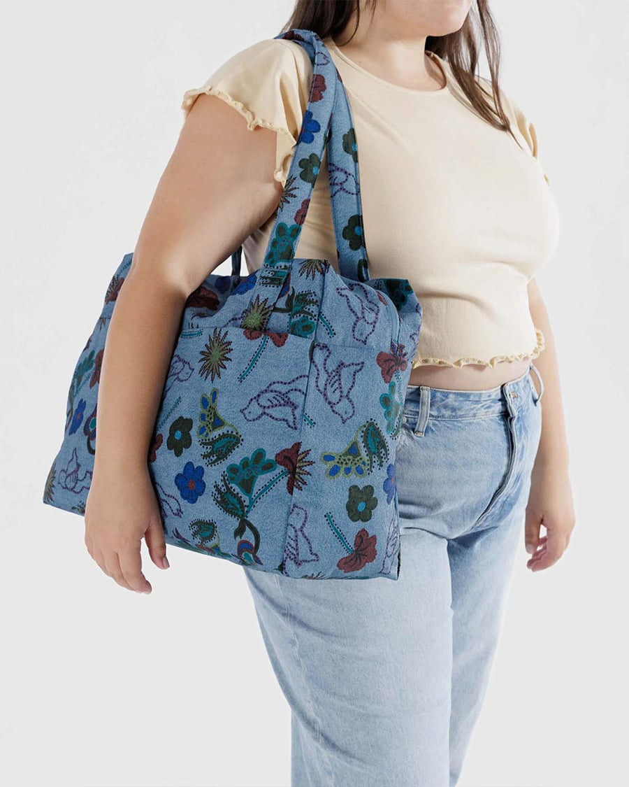 model carrying blue digital denim nylon cloud carry on bag with colorful floral and bird print