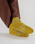 model wearing mustard yellow baggu socks with ice blue smiley faces