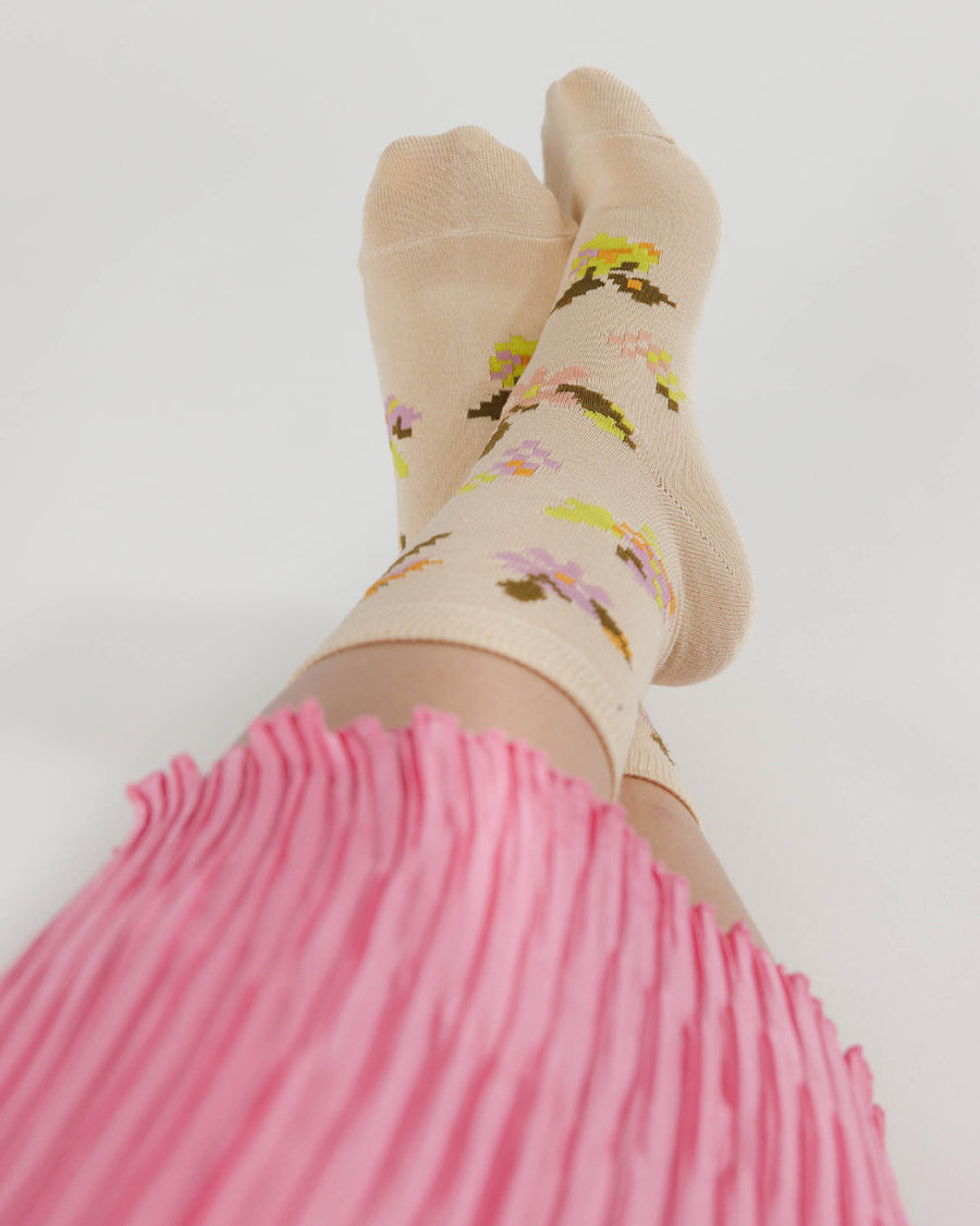 model wearing tan socks with orange, yellow and pink needlepoint floral design