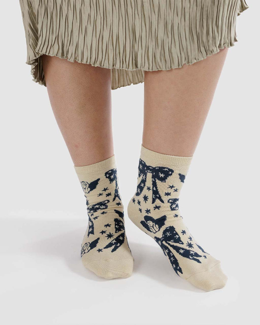 model wearing cream crew socks with navy cherub and bow print