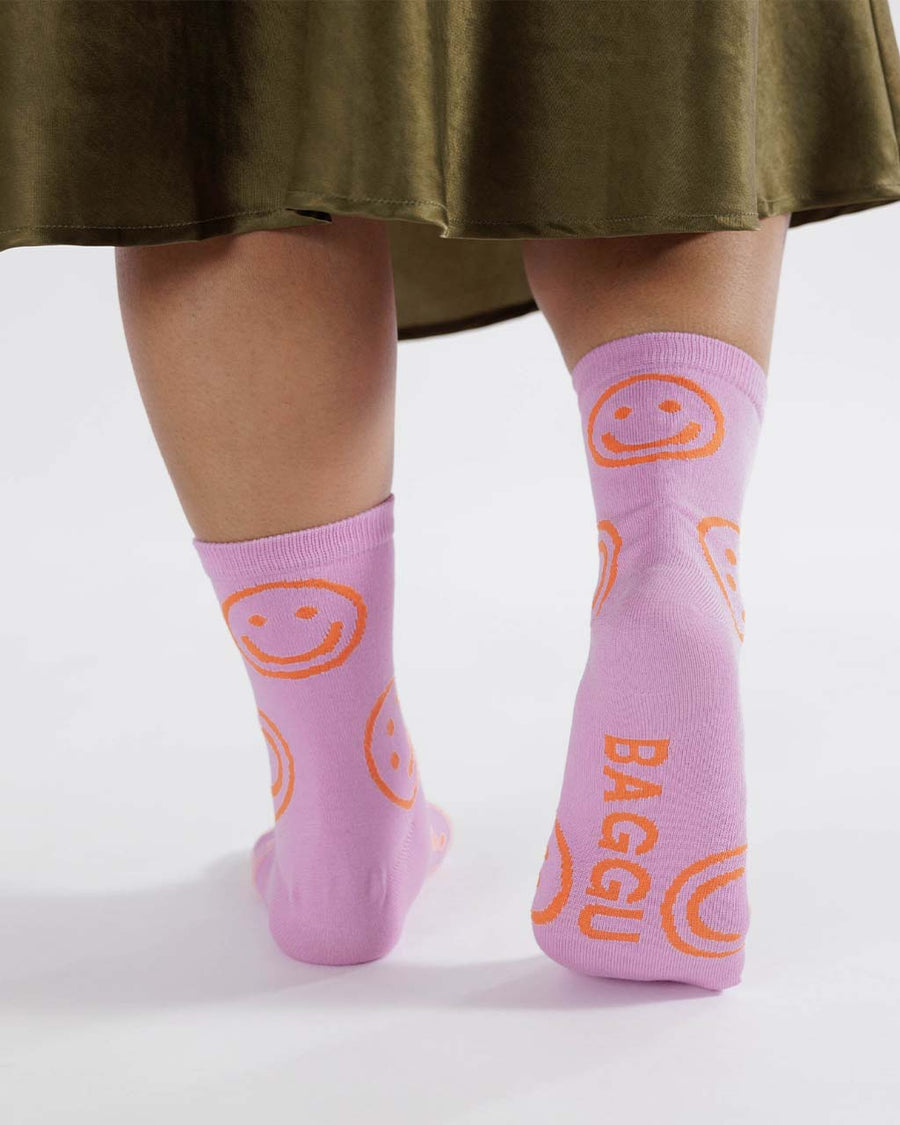 model wearing bright pink crew socks with orange smiley face design