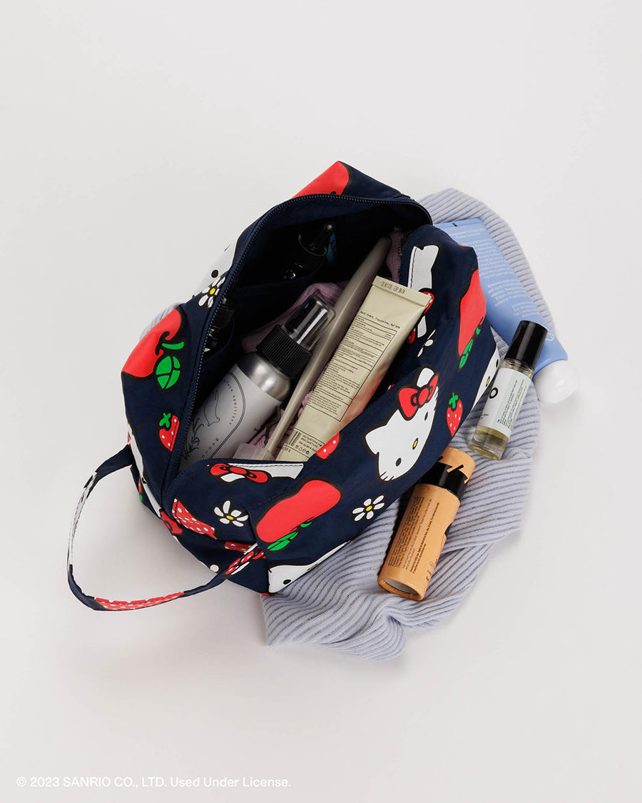 navy dopp kit with all over hello kitty face and apple print filled with cosmetics