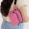 model wearing bright pink fanny pack with black strap