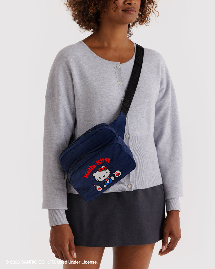 model wearing navy fanny pack with embroidered hello kitty with a milkshake and fishbowl as a crossbody