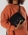 model wearing black fanny pack with colorful cross stitch design