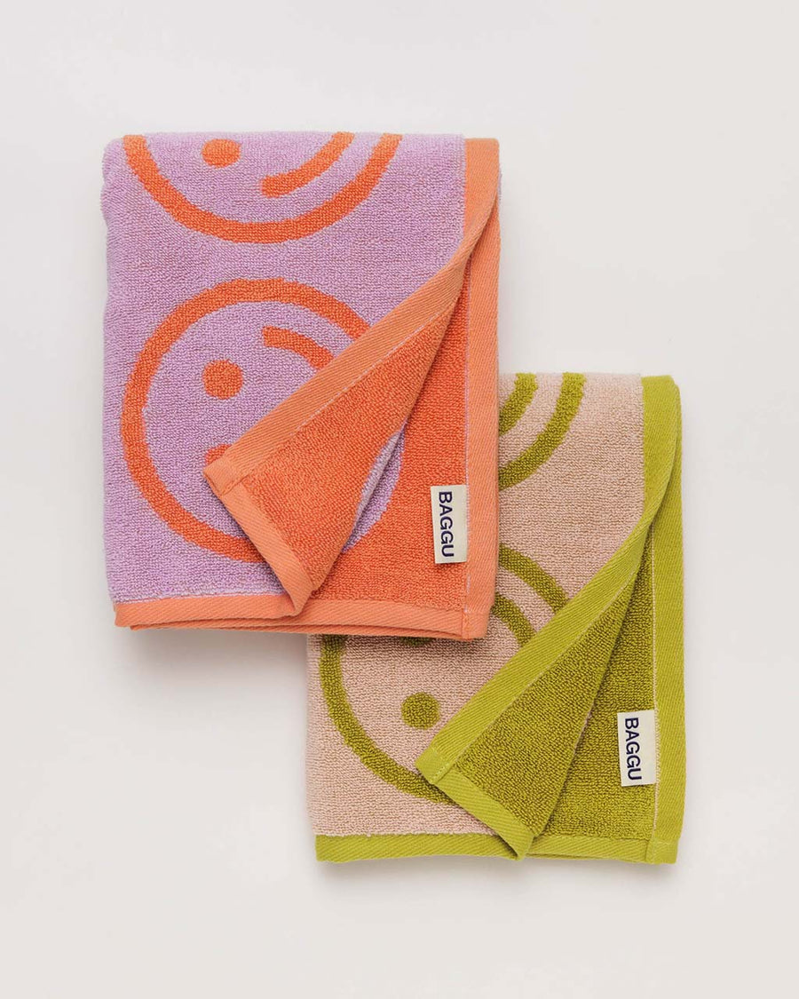 set of two baggu hand towels: lilac with coral smilies, and peach with ochre smilies