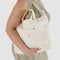 model holding cream horizontal zip duck bag with rainbow heart embroidery 