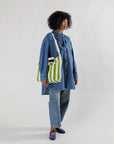 model wearing green and cream vertical stripe horizontal zip duck bag on their shoulder