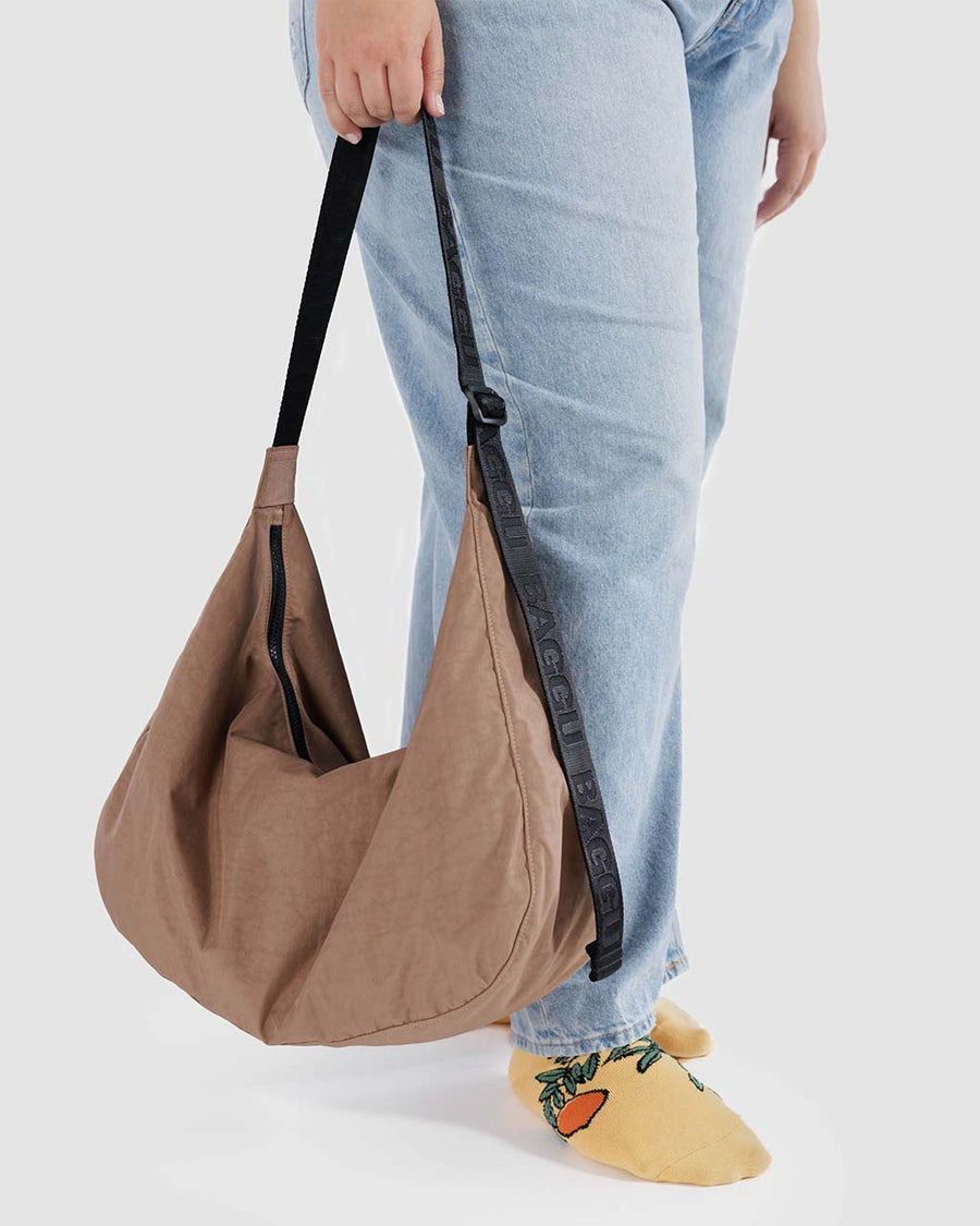 model holding light brown large nylon crescent bag
