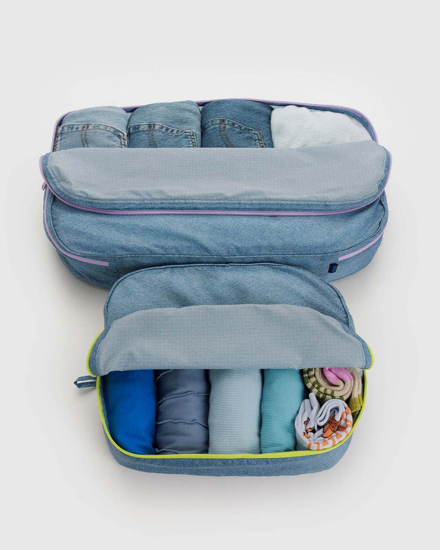 set of two large packing cubes in digital denim print with neon zippers filled with jeans