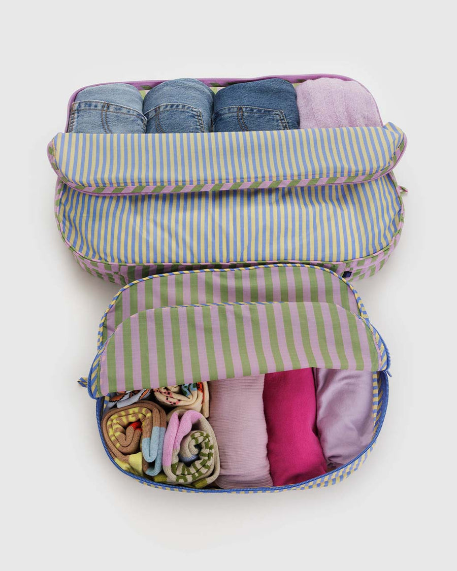 two large packing cube sets with various colorful stripe patterns and blue and lavender zippers filled with clothing