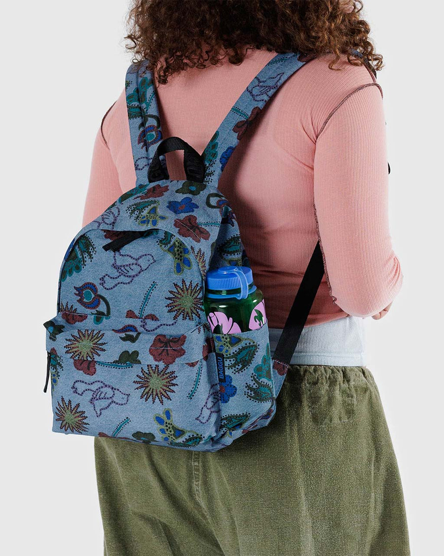 model wearing denim blue medium nylon backpack with all over floral and bird print
