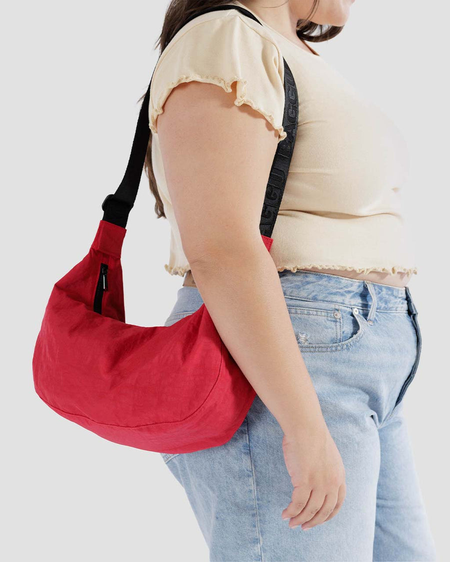 model wearing candy apple red medium nylon crescent bag