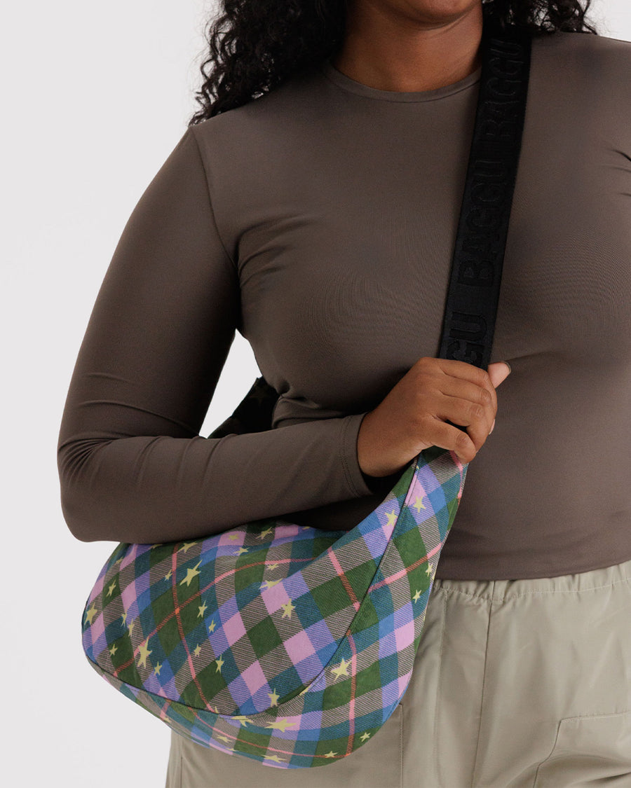 model carrying medium crescent bag with green, blue and pink plaid with yellow stars