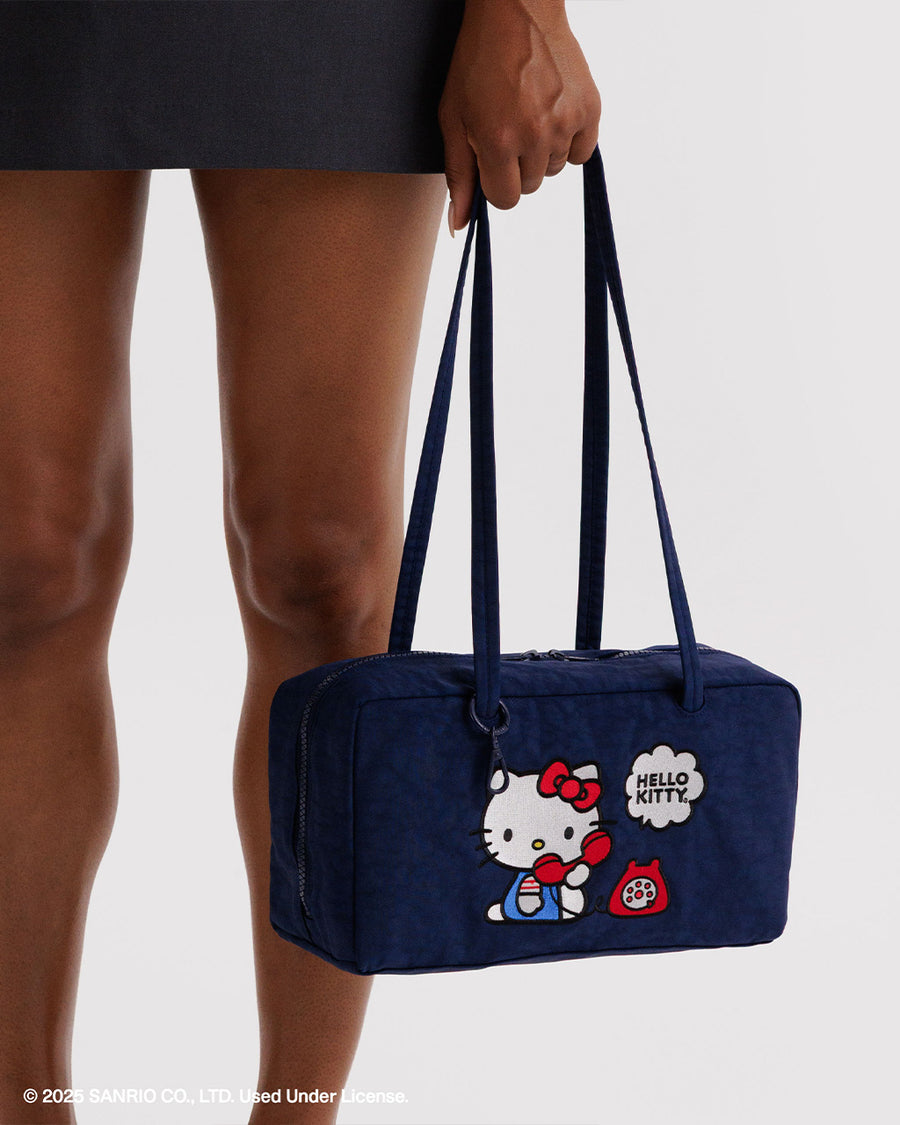 model holding navy nylon bowler bag with embroidered hello kitty talking on a red phone
