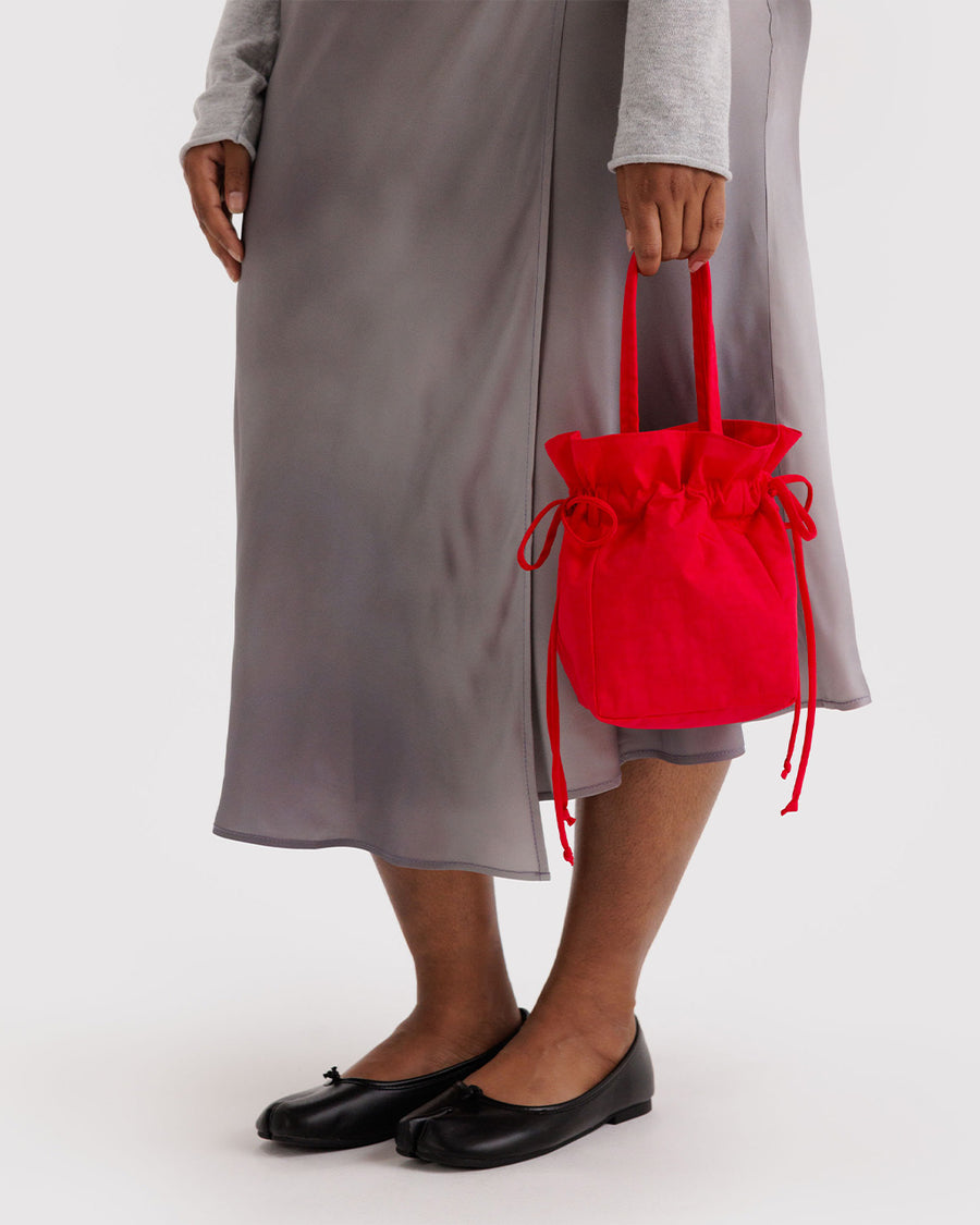 model holding red drawstring bag with handle