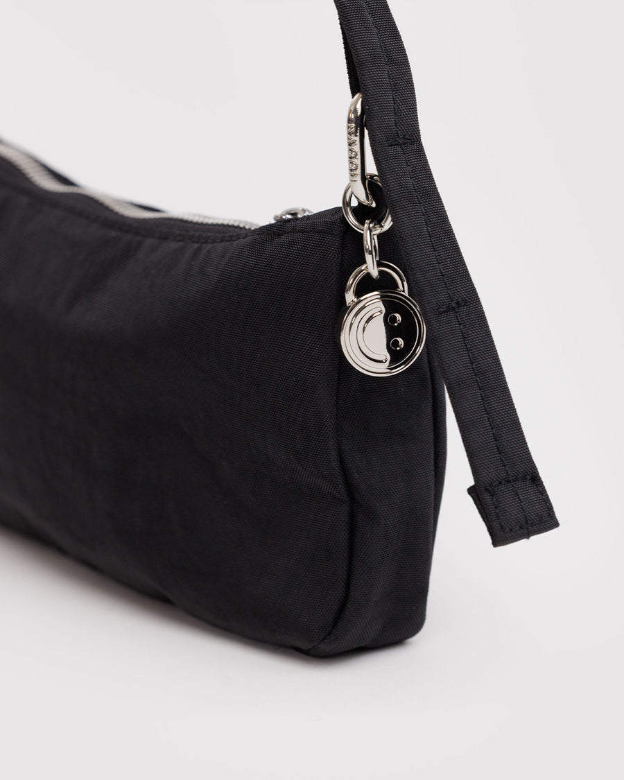 up close of charm on nylon pochette bag with smiley charm and adjustable shoulder strap
