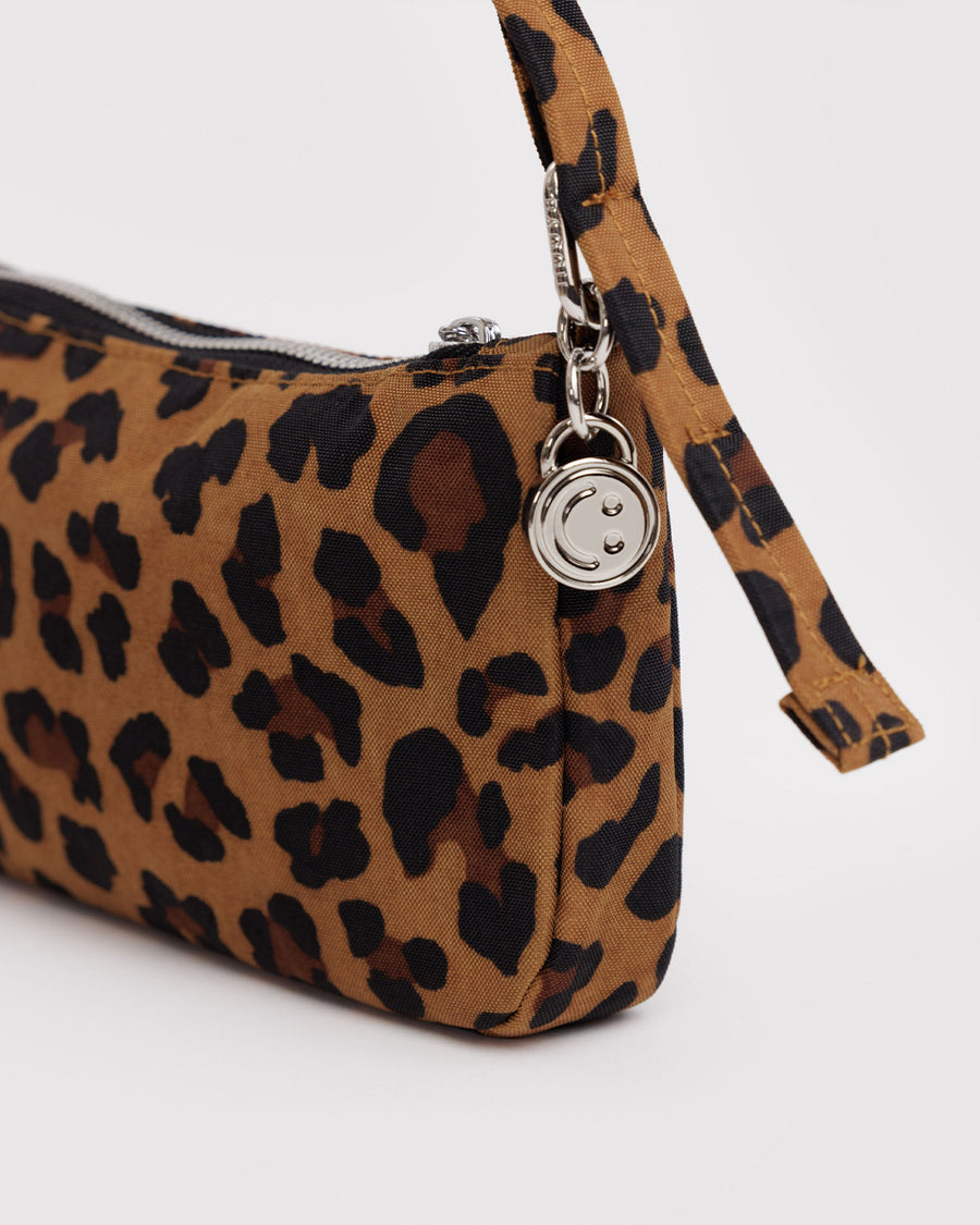 up close of charm on nylon leopard pochette bag with smiley charm and adjustable shoulder strap