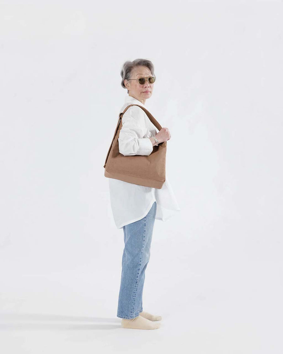 model carrying light brown nylon shoulder bag