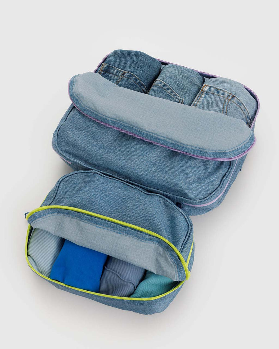set of two digital denim packing cubes with neon zippers filled with clothing