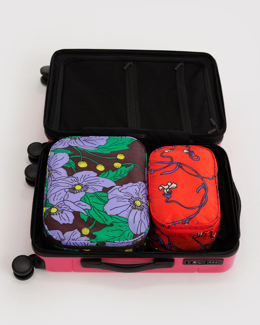 set of two packing cubes: small coral snapdragon and large maroon poppy in suitcase