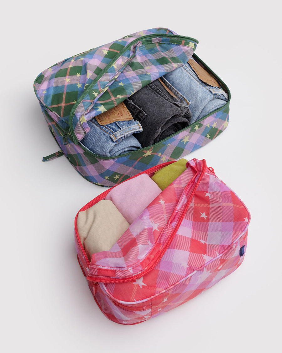 set of two packing cubes: small pink plaid star and large blue/green plaid star with clothing inside