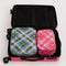 set of two packing cubes: small pink plaid star and large blue/green plaid star in a suitcase