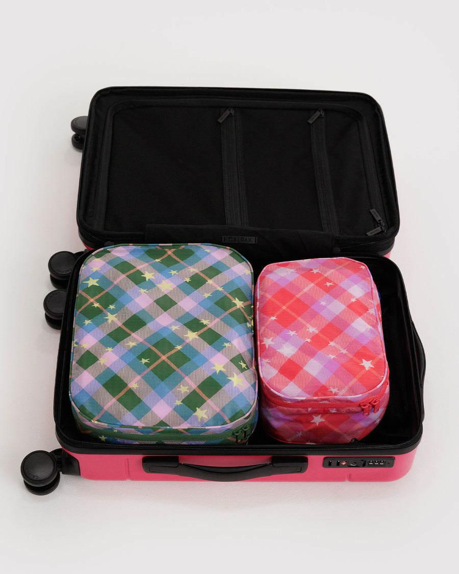 set of two packing cubes: small pink plaid star and large blue/green plaid star in a suitcase
