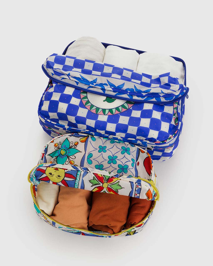 set of 2 packing cubes: white vacation tiles and blue checkered cherry print with items inside