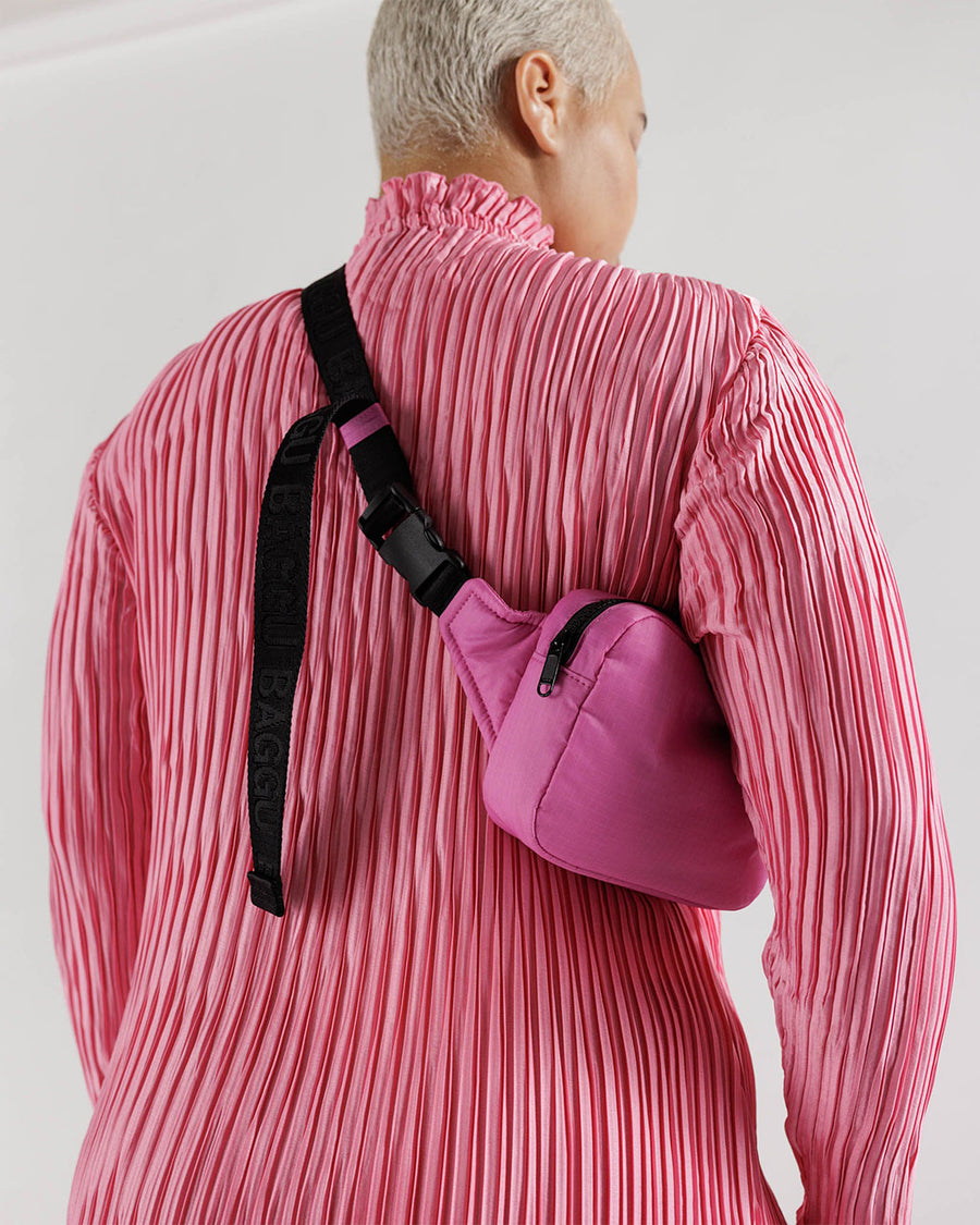 model wearing extra pink puffy fanny pack with black strap
