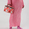 model holding pink puffy baggu lunch box with hello kitty face, apple, and strawberry print