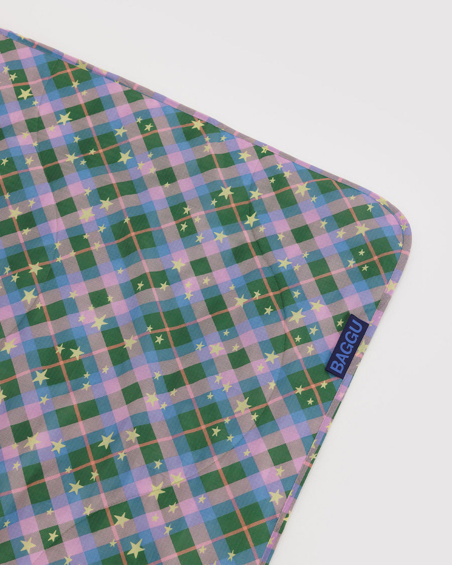 flattened pink, green, and blue plaid puffy picnic blanket with pale yellow star print