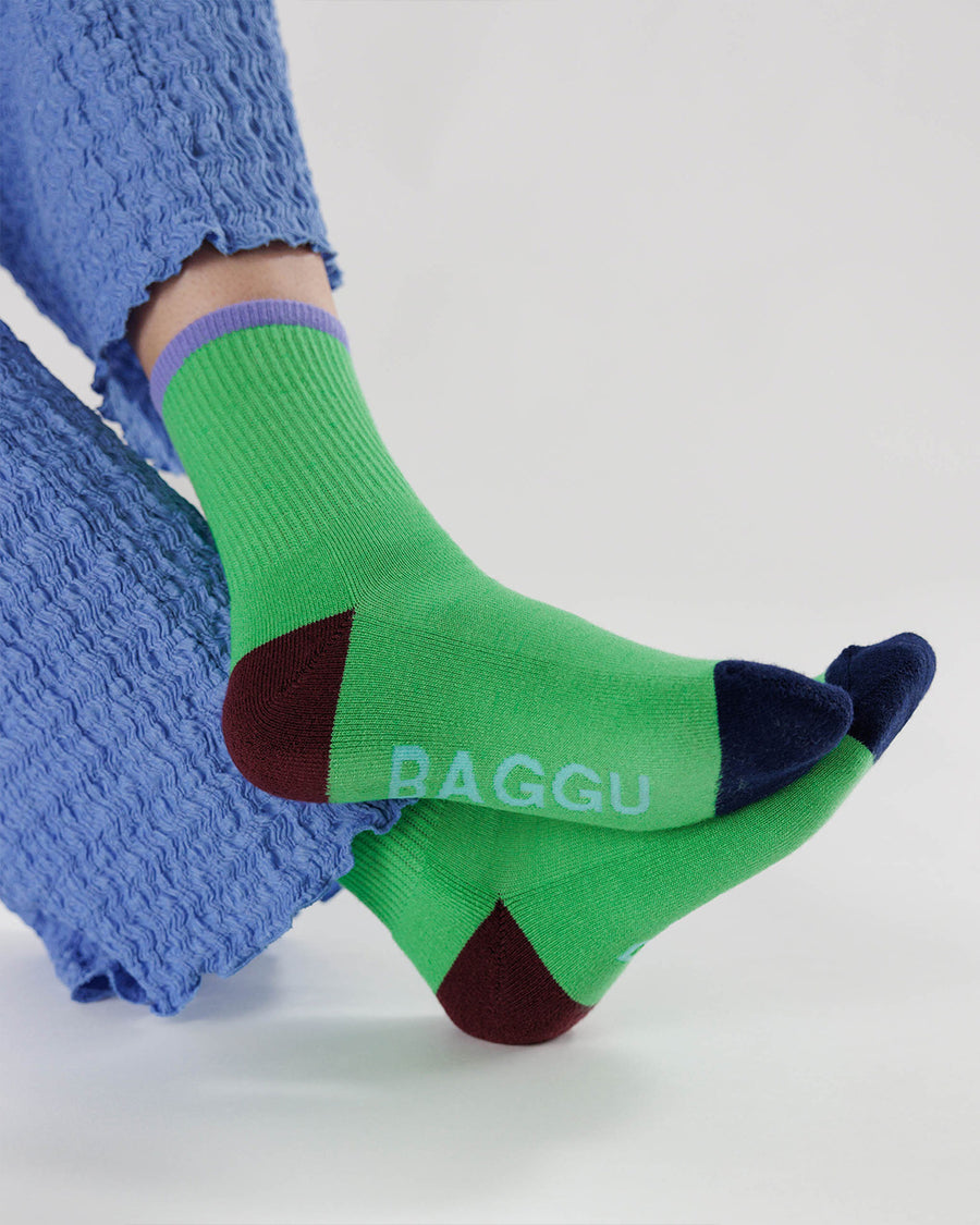model wearing bright green ribbed crew socks with periwinkle, brown and black accents