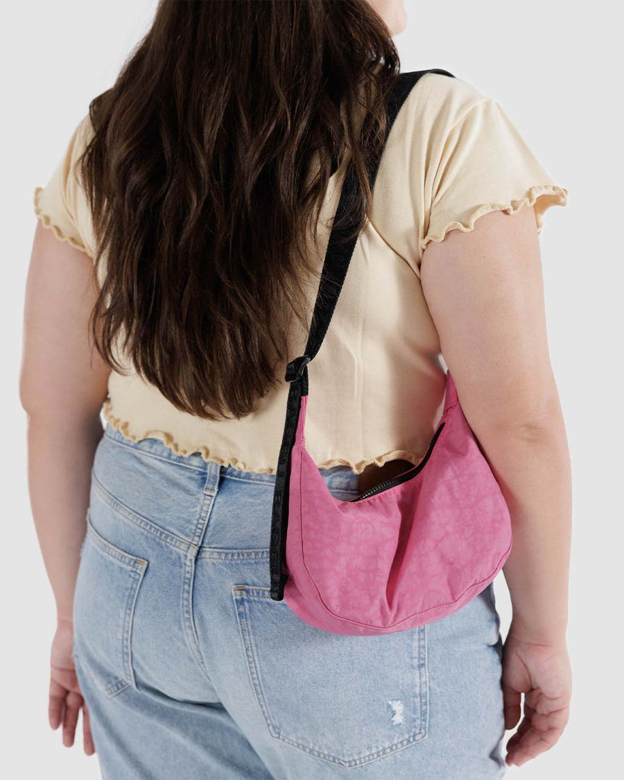 model wearing bright pink small nylon crescent bag