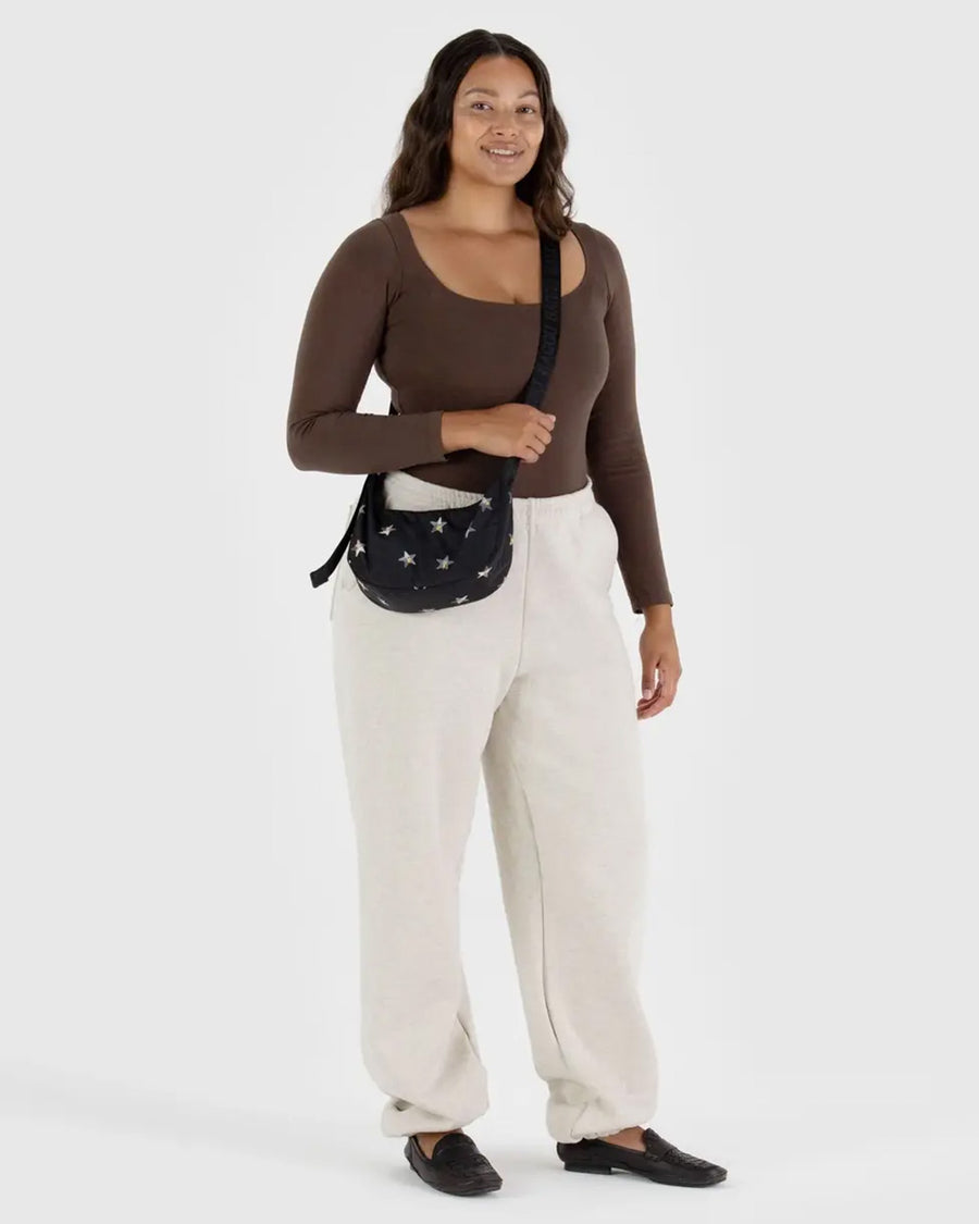 model wearing black small nylon crescent bag with silver holographic stars