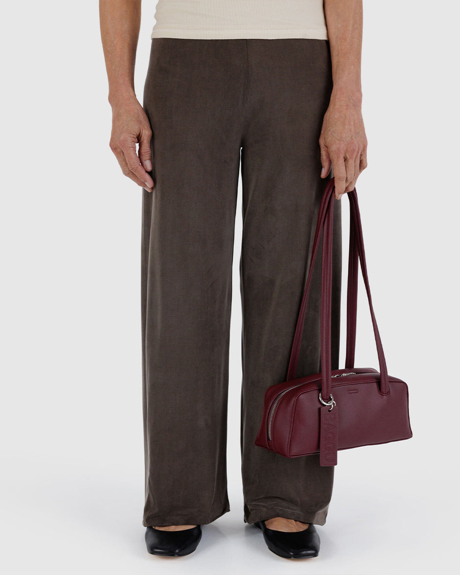 model holding mahogany small dome recycled leather bowler bag with silver charm clasp