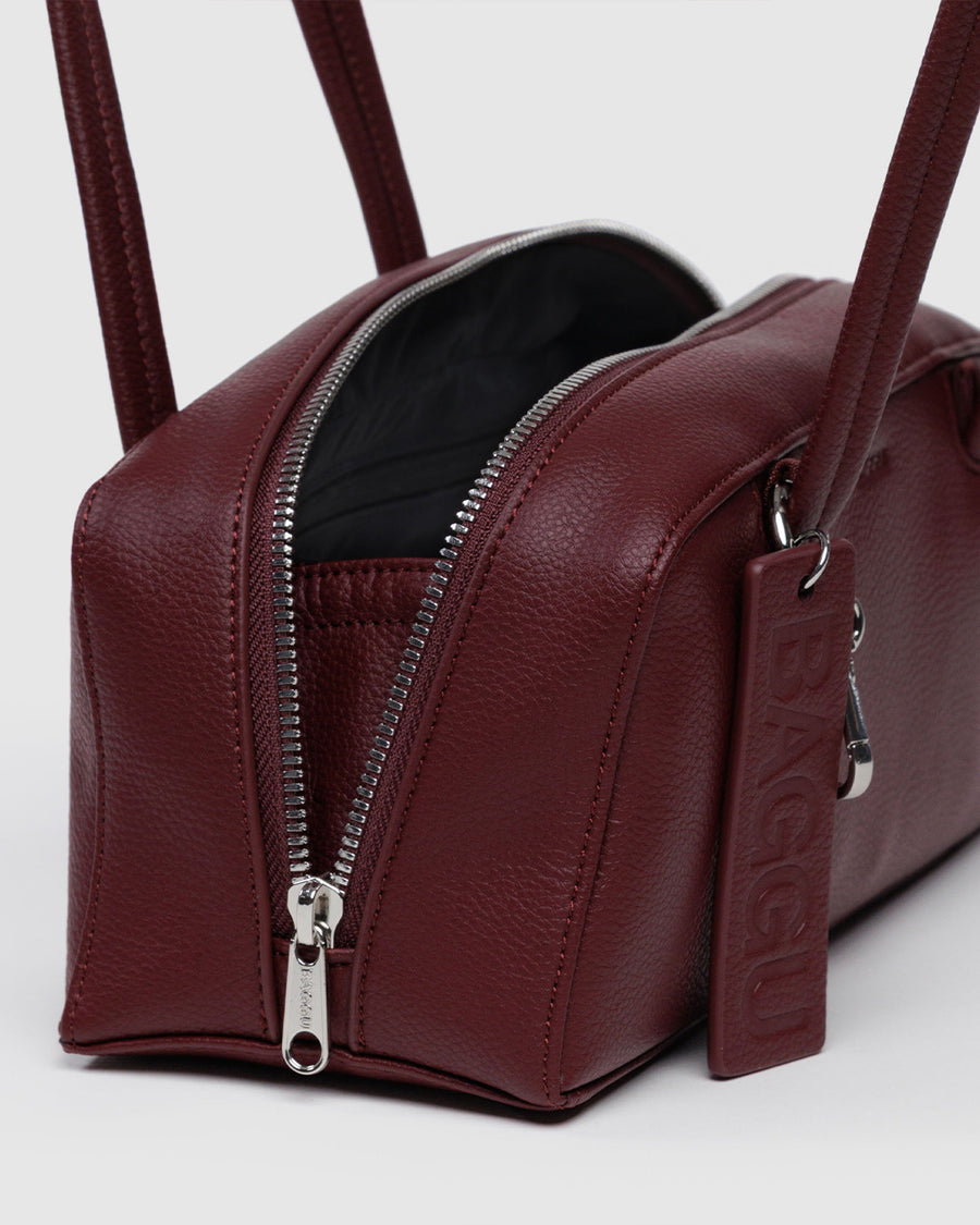 side view of mahogany small dome recycled leather bowler bag with silver charm clasp