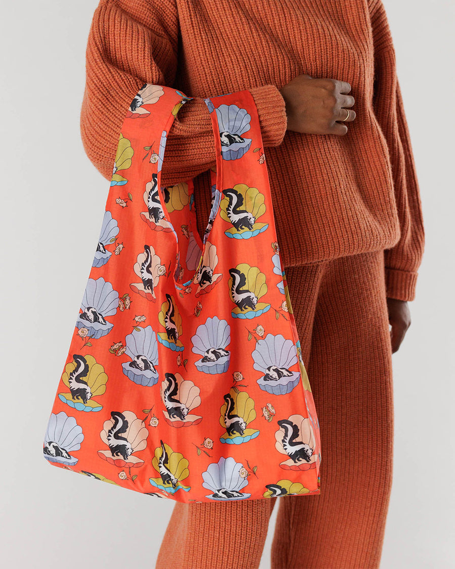 model carrying coral standard baggu with skunk in a seashell print