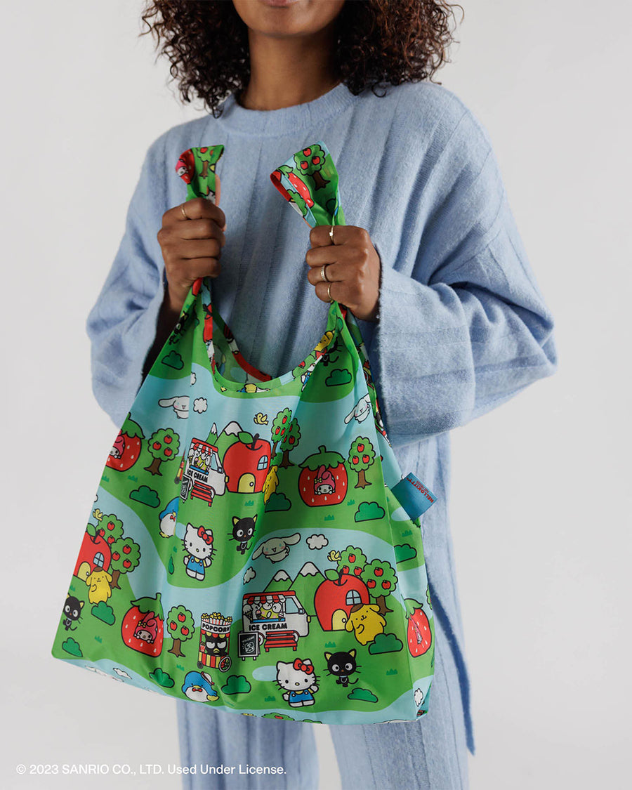model holding standard baggu with hello kitty and friends village scene