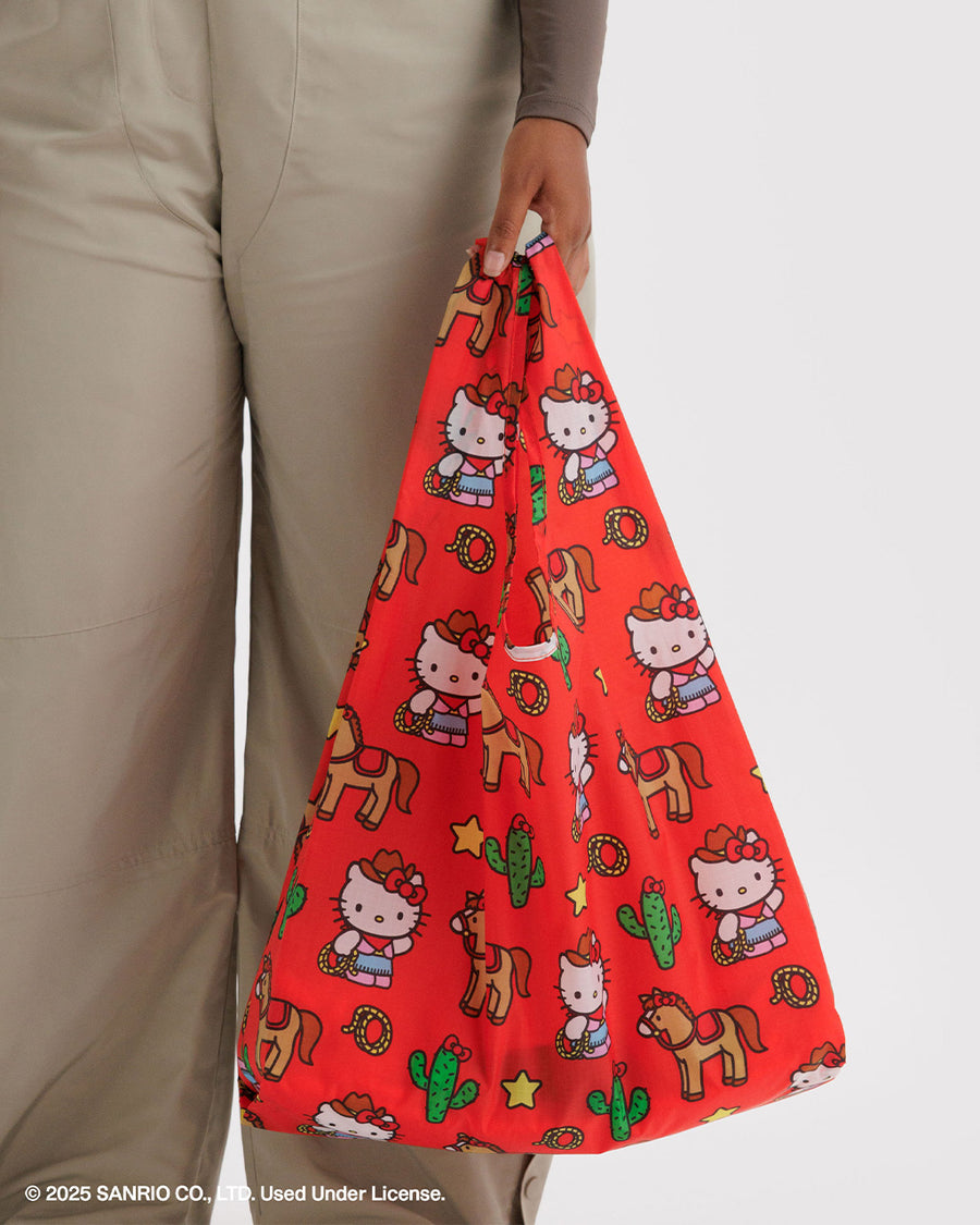 model carrying coral standard baggu with western hello kitty with horse, cactus, lasso, and star print