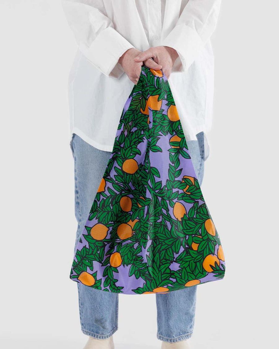 model holding periwinkle standard baggu with orange tree print