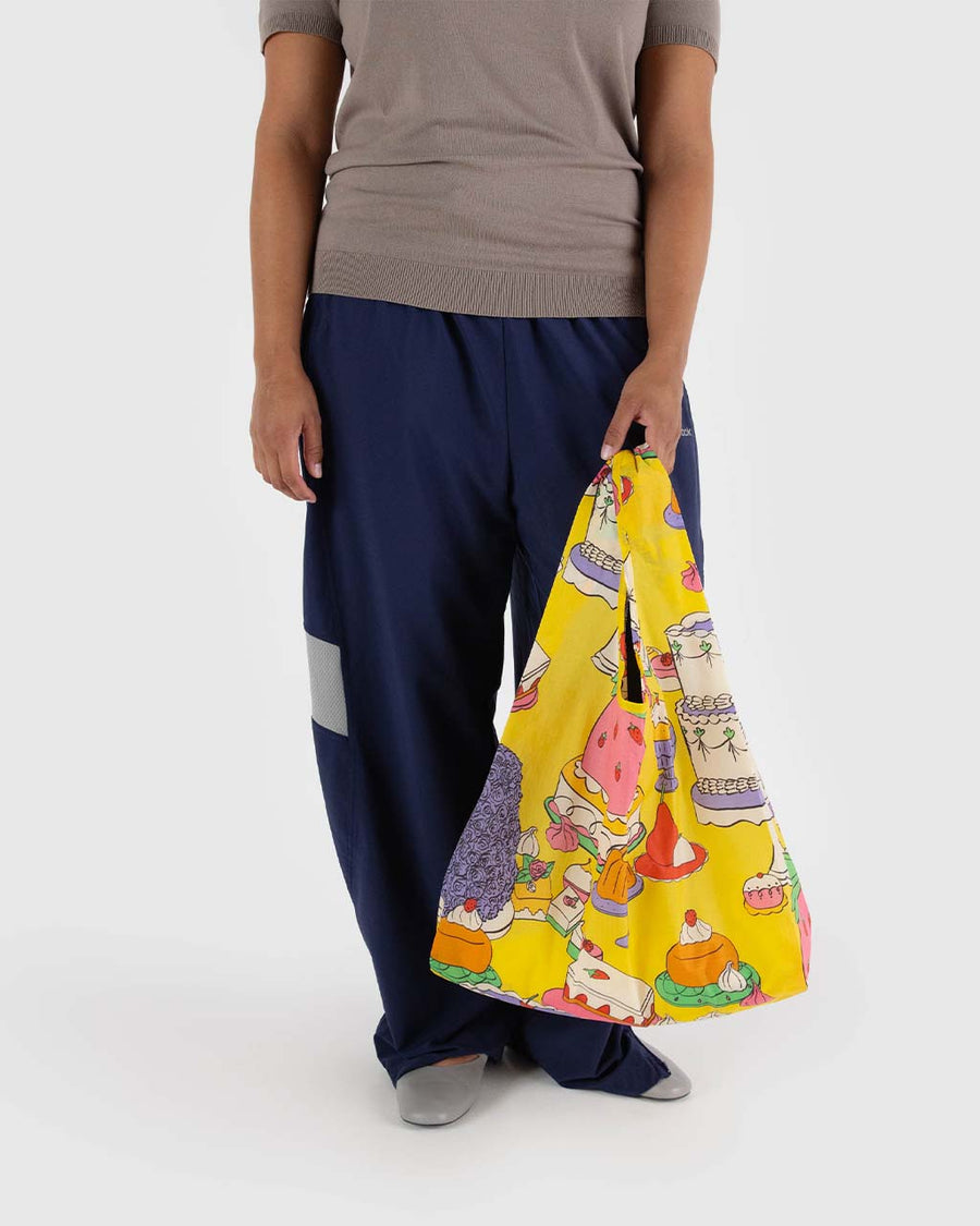 model holding yellow standard baggu with colorful cake/pastry print