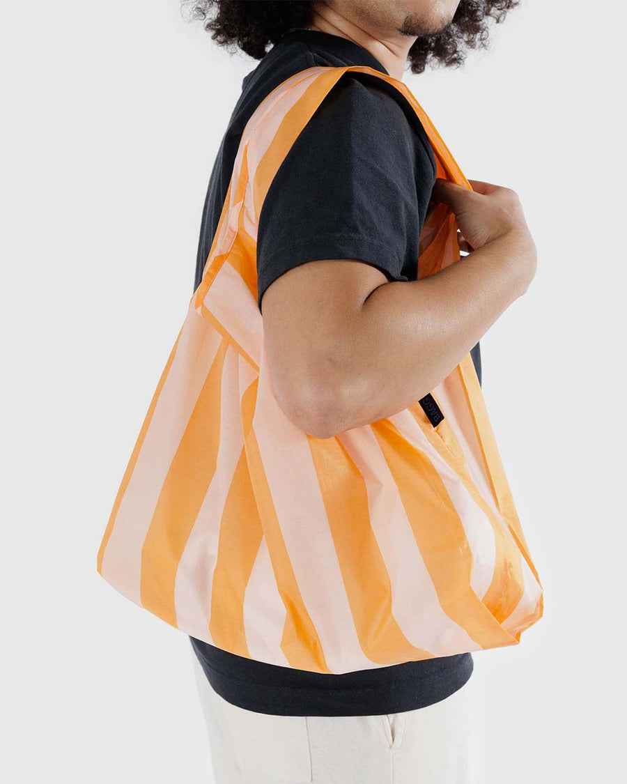 model carrying orange and white thick stripe standard baggu